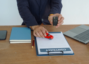 desk with contract on desk with person holding car key
